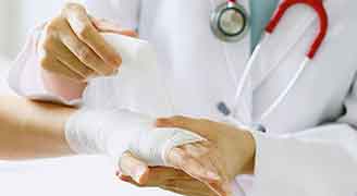 Close-up of female doctor with stethoscope bandaging hand of patient.